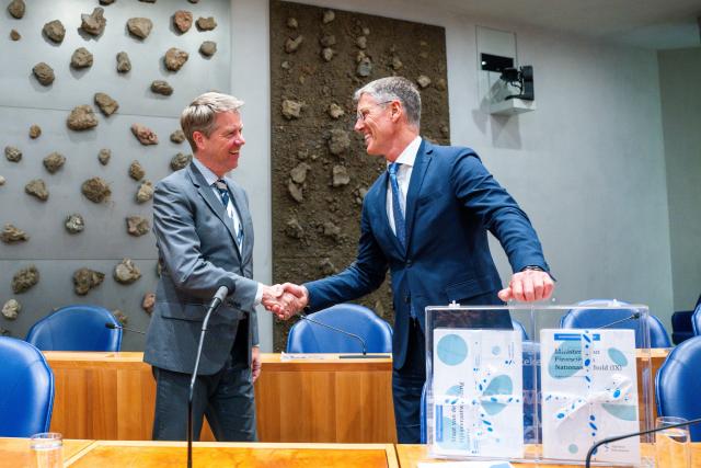 Kamervoorzitter Martin Bosma schudt de hand van Pieter Duisenberg, president van de Algemene Rekenkamer, in de plenaire zaal. Voor hen staat het koffertje met de stukken die de Rekenkamer aanbiedt.