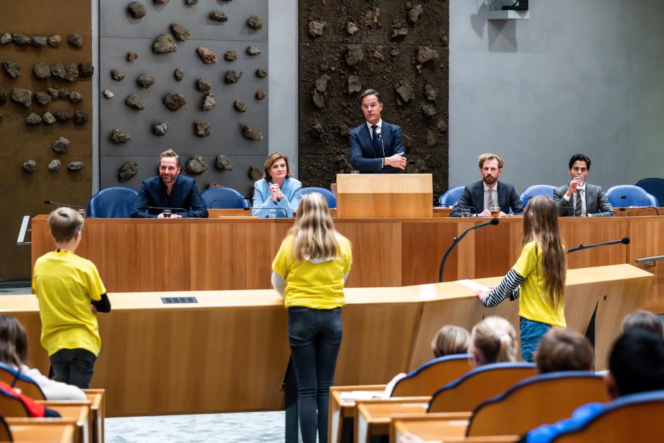 Kinderen staan in de plenaire zaal bij de interruptiemicrofoon. In vak K zitten vier bewindslieden, minister-president Mark Rutte staat achter de microfoon.