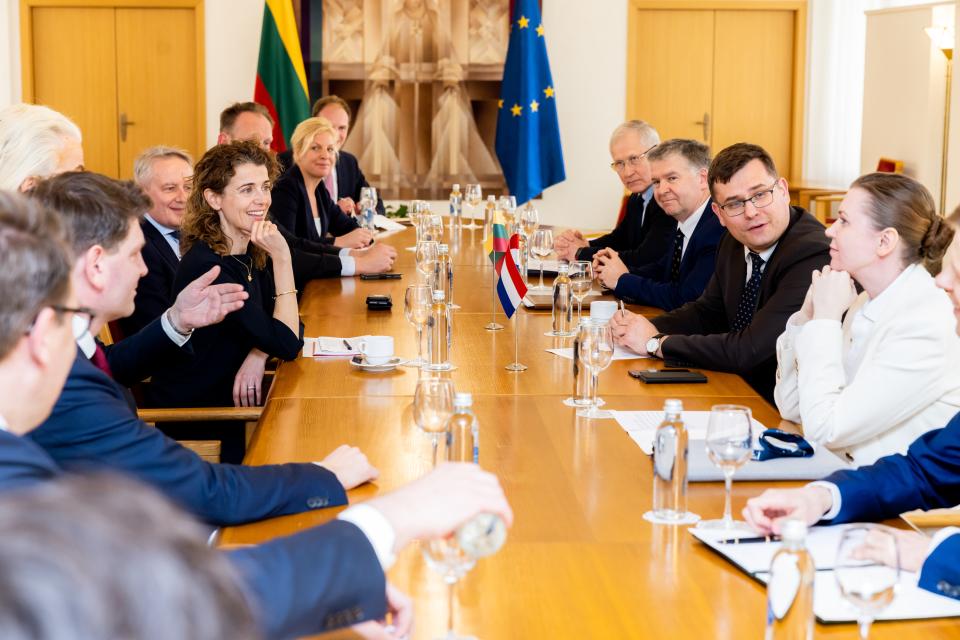 In het Litouwse parlement spreken Kamerleden met de commissie voor Nationale Veiligheid en Defensie, zittend aan een tafel met vlaggen op de achtergrond.