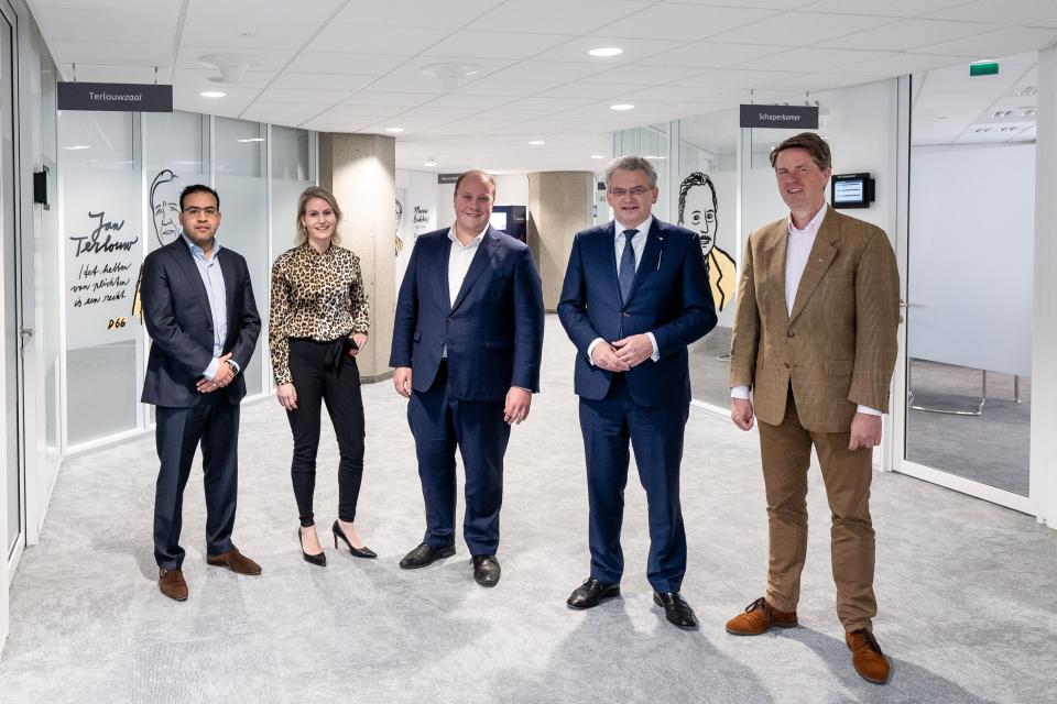 Vijf Kamerleden staan op een rij in een gang van het tijdelijke gebouw van de Tweede Kamer.