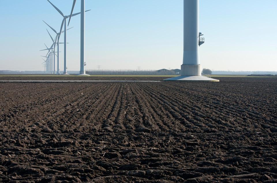 Een rij windmolens in een vlak, kaal landschap