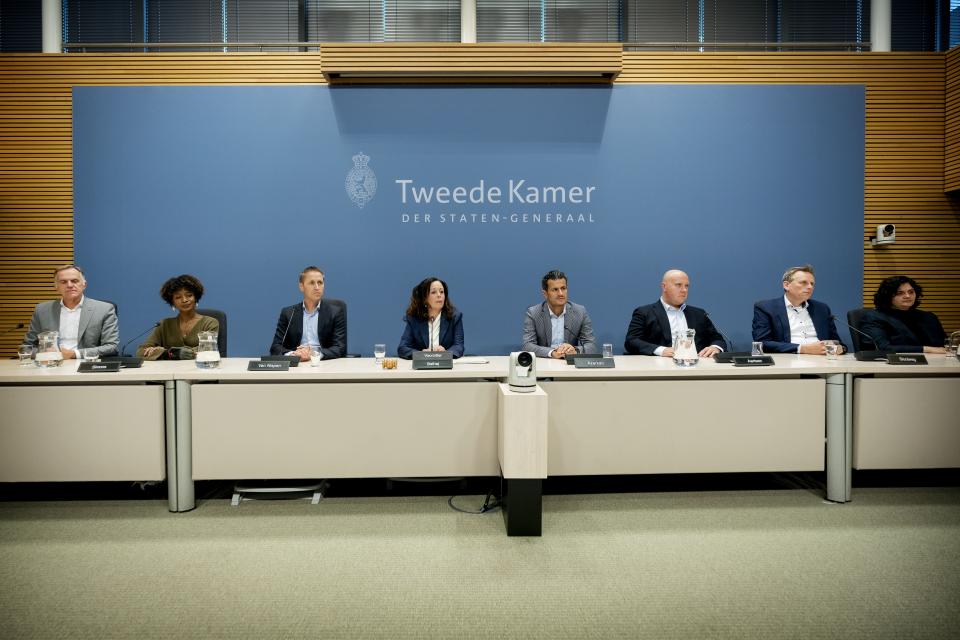 De commissieleden in de enquêtezaal. V.l.n.r.: Lammert van Raan (PvdD), Sylvana Simons (Bij1), Michiel van Nispen (SP, vicevoorzitter), Salima Belhaj (D66, voorzitter), Farid Azarkan (Denk), Thierry Aartsen (VVD), Evert Jan Slootweg (CDA) en Senna Maatoug (GroenLinks).  