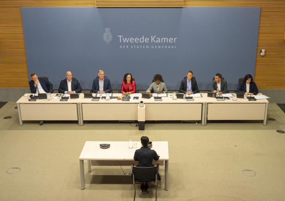 De leden van de parlementaire enquêtecommissie Fraudebeleid en Dienstverlening zitten achter een tafel in de Enquêtezaal. Voor hen zit gedupeerde Dulce Gonçalves-Tavares aan een tafel.