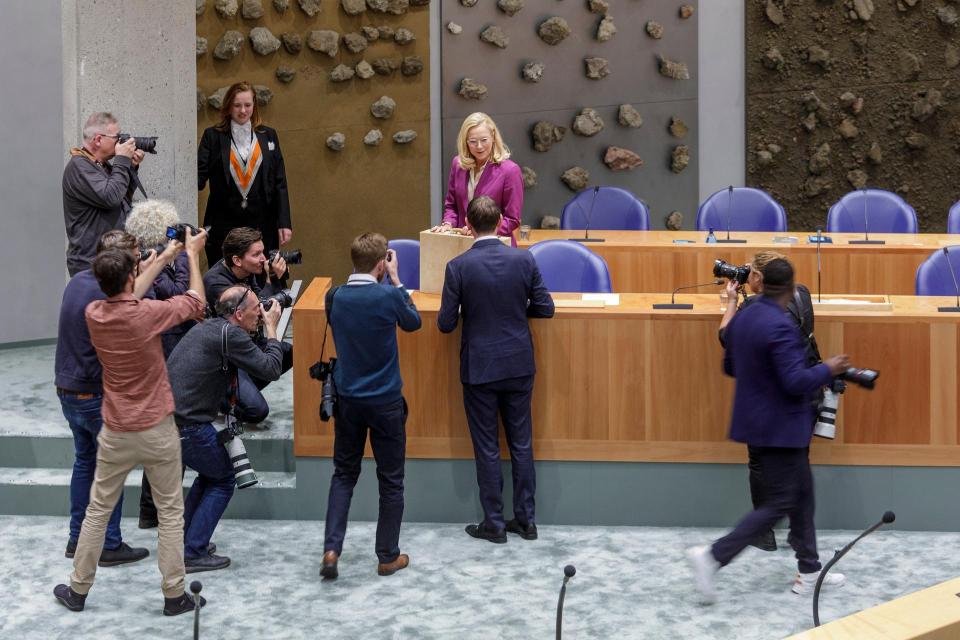 Minister Kaag van Financiën houdt koffertje vast in plenaire zaal, voor haar staan enkele fotografen. 