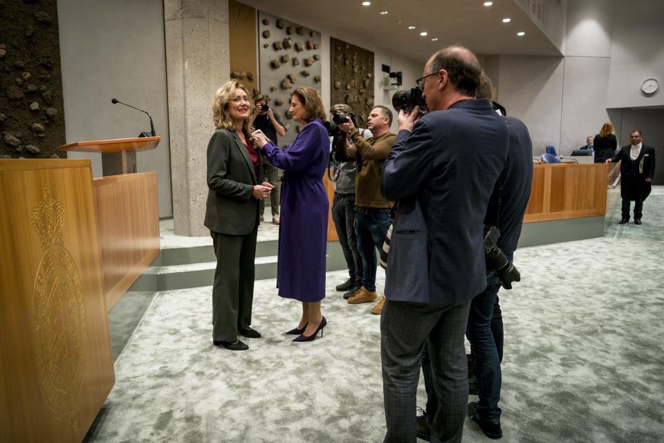 Kamervoorzitter Vera Bergkamp krijgt in de plenaire zaal een lintje opgespeld door vicepremier Karien van Gennip. Een aantal fotografen maken foto's.