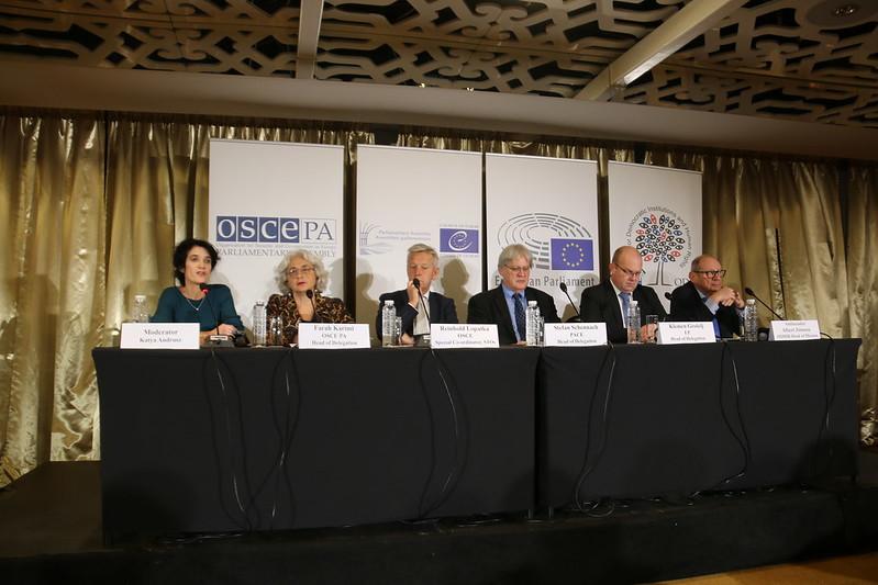 Kamerleden zitten aan een tafel bij de persconferentie