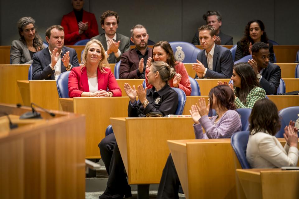 Lilian Marijnissen zit in de plenaire zaal en is omringd door zittende en applaudisserende Kamerleden