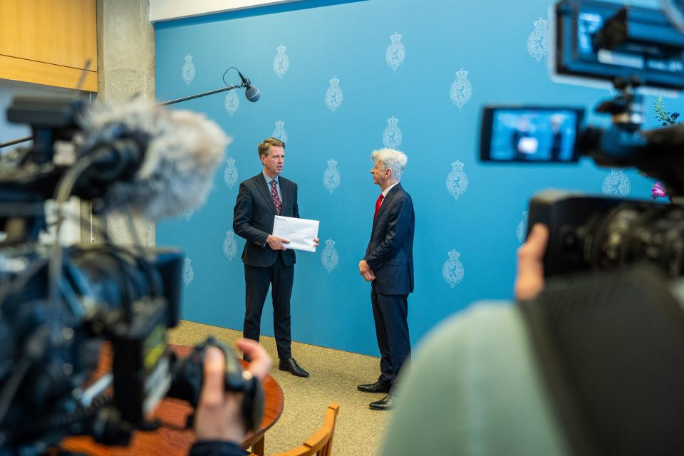 Kamervoorzitter Martin Bosma staat met het eindrapport in zijn handen en praat met informateur Ronald Plasterk. Op de voorgrond camera's van journalisten.