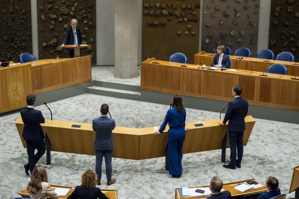 Kamerlid Geert Wilders aan het woord in de plenaire zaal. Informateur Kim Putters zit in vak K. Op de voorgrond staan Kamerleden bij de interruptiemicrofoon. 