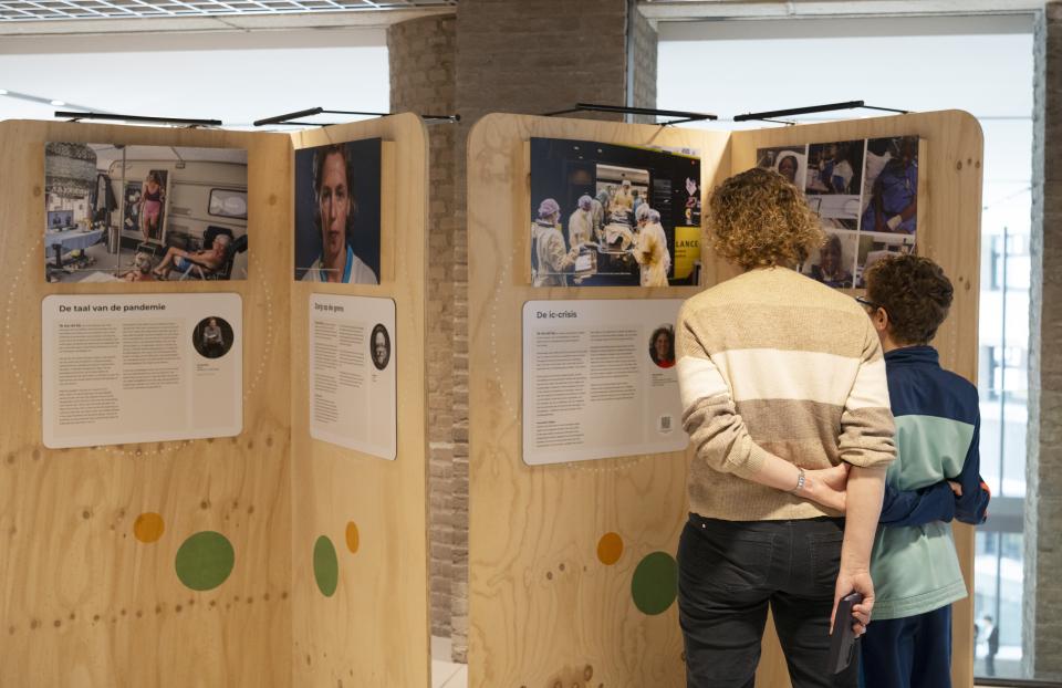 Twee bezoekers bekijken foto's en teksten die op panelen staan.