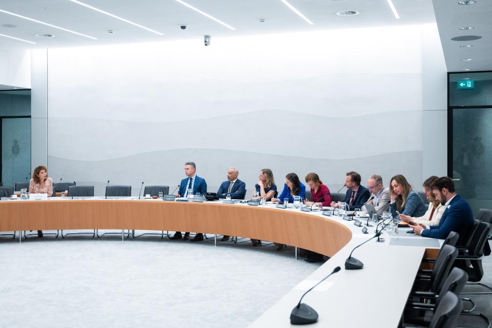 Aan een halfronde tafel zit links de kandidaat-bewindspersoon voor Klimaat en Groene Groei en rechts de commissieleden.