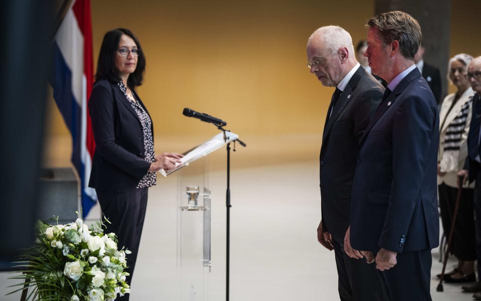 Eerste Kamervoorzitter Jan Anthonie Bruijn (links) en Tweede Kamervoorzitter Martin Bosma staan voor een krans in de Statenpassage. Op de achtergrond Nanette van Beukering (secretaris Stichting Nationale Herdenking 15 augustus 1945) bij de Nederlandse vlag.