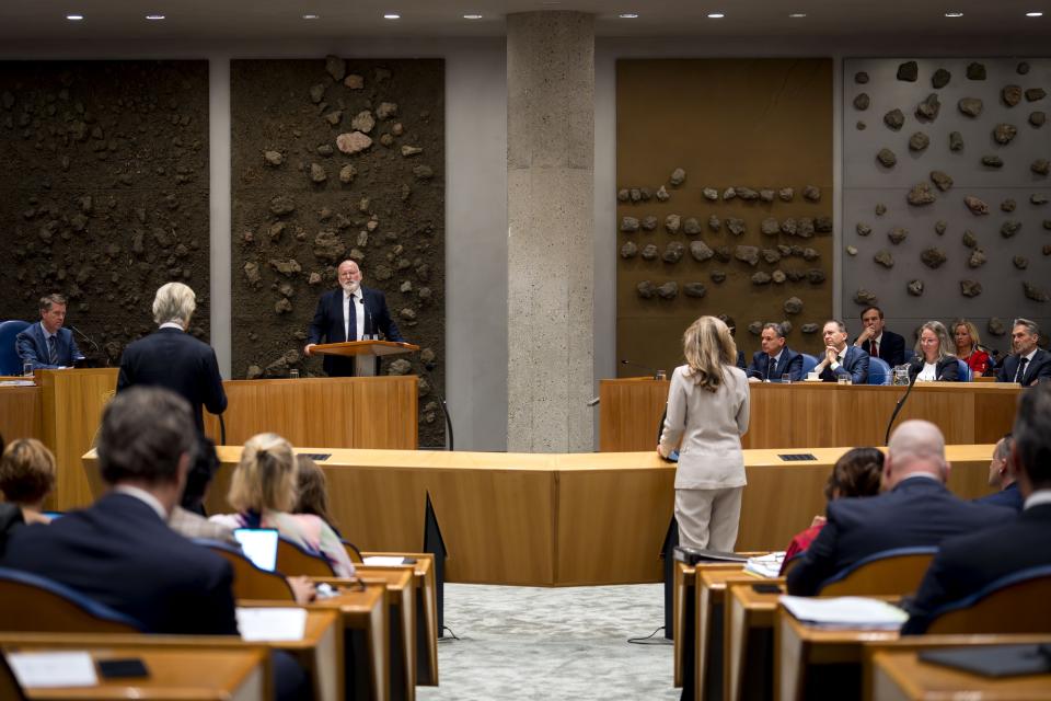 Beeld van debat in plenaire zaal. Kamerleden in hun bankjes en aan de interruptiemicrofoon op de rug gezien. 