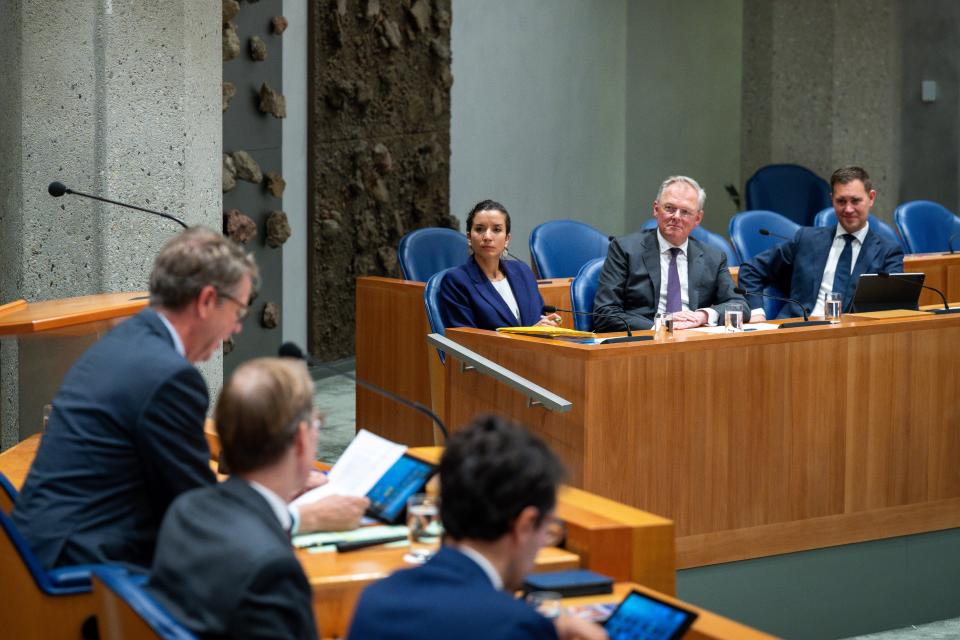 In vak K van de plenaire zaal zitten van links naar rechts Nora Achahbar (Toeslagen en Douane), Folkert Idsinga (Fiscaliteit en Belastingdienst) en minister van Financiën Eelco Heinen. Op de voorgrond opent Kamervoorzitter Martin Bosma de vergadering. 