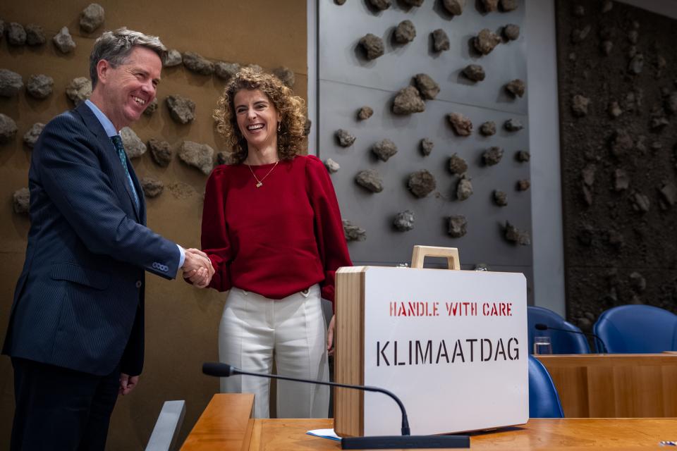 Minister Hermans geeft Voorzitter Bosma een hand. Voor hen staat het Klimaatkoffertje