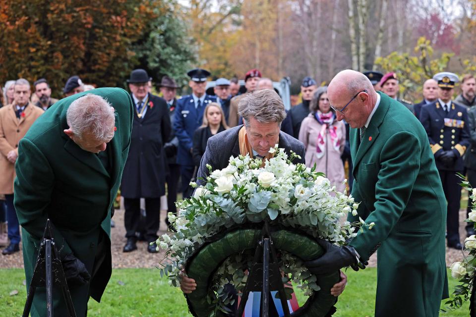 Een krans op een standaard van achteren gezien, ervoor Kamervoorzitter Martin Bosma en links en rechts twee heren in groen kostuum. Daarachter staand publiek in rijen opgesteld. 