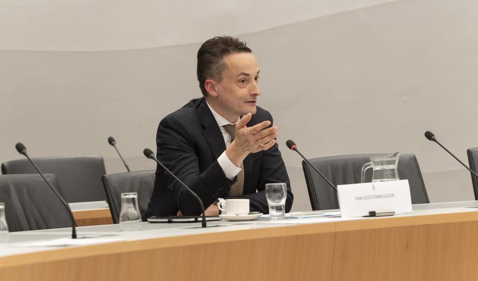 Kandidaat-staatssecretaris van Financiën Tjebbe van Oostenbruggen zit achter een tafel met een microfoon en een naambordje.