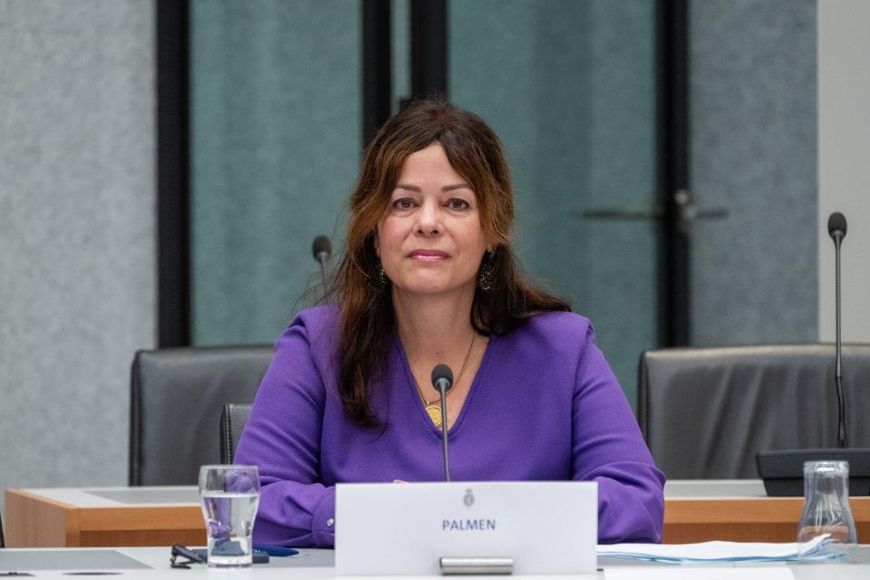 Sandra Palmen-Schlangen tijdens de openbare hoorzitting zittend achter een tafel in een commissiezaal.