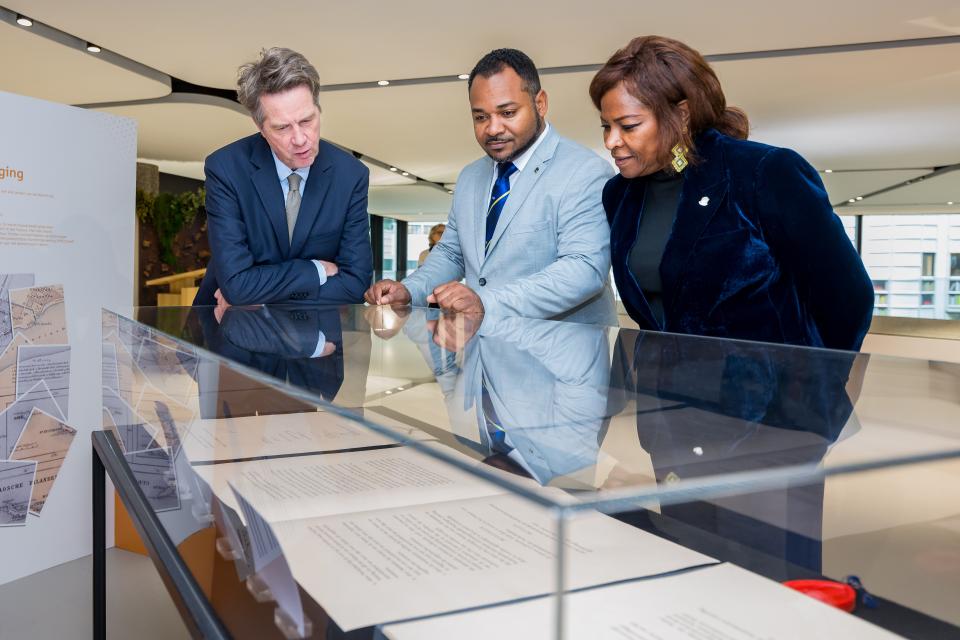 Kamervoorzitter Martin Bosma, Carlson Manuel, gevolmachtigde minister van Curaçao, en Gracita Arrindell, gevolmachtigde minister van Sint Maarten, bekijken het Statuut dat in een vitrine ligt.