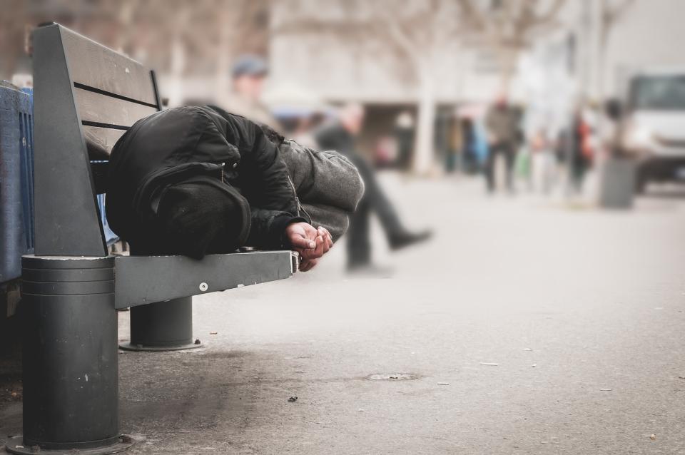 Man ligt op een openbaar bankje op straat te slapen