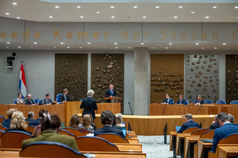 Beeld van de plenaire zaal, van achteren gefotografeerd. Op de rug gezien PVV-fractievoorzitter Geert Wilders bij de interruptiemicrofoon en GroenLinks-PvdA-fractievoorzitter Frans Timmermans achter het spreekgestoelte. 