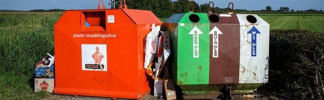 Een rode en groene container naast elkaar op straat laten zien hoe afval (plastic en glas) gescheiden worden. 