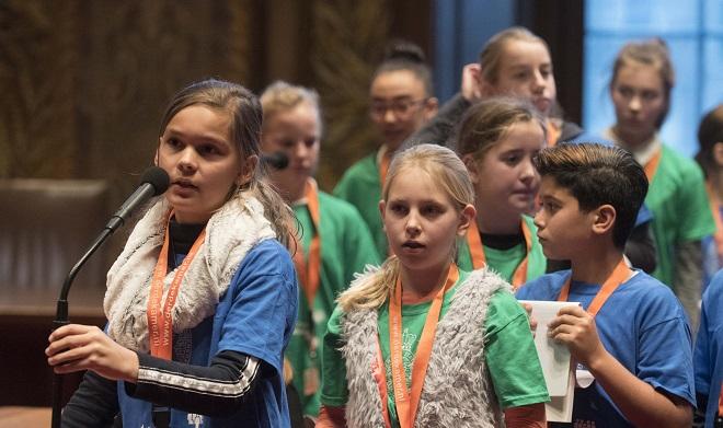 Leerlingen uit groep 7 en 8 staan voor de interruptiemicrofoon van de Eerste Kamer