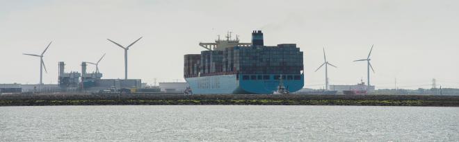 Water op de voorgrond, een containerschip op de achtergrond. 