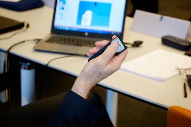 Beeldscherm en hand met afstandsbediening: iemand bedient een presentatie op de laptop