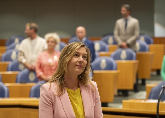 Kamerlid Nicole Temmink staat in de plenaire zaal. Kamerleden zijn voor haar opgestaan.