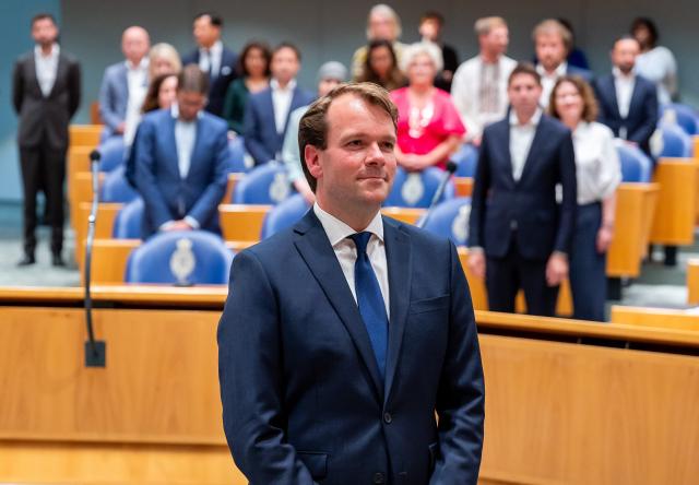 Kamerlid Hans Teunissen staat in de plenaire zaal. Kamerleden zijn opgestaan voor dit moment.