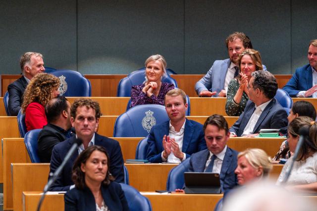 Kamerlid Leonie Vestering zit in de Plenaire zaal en de Kamerleden rondom haar applaudiseren.