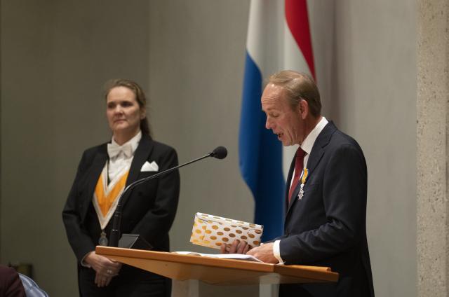 Kamerlid Kees van der Staaij laat achter het spreekgestoelte de handreiking zien die hij samen met Kamerlid Joost Sneller heeft gemaakt.