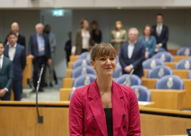 Sarah Dobbe staat voorin de plenaire zaal om beëdigd te worden. Achter haar kijken Kamerleden staand toe.