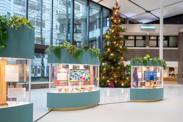 Middenin de centrale hal van de Tweede Kamer staan drie vitrines. Daarachter staat de kerstboom.