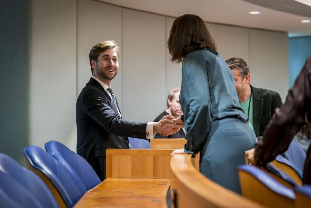 Freek Jansen schudt de hand van een ander Kamerlid achterin de plenaire zaal.