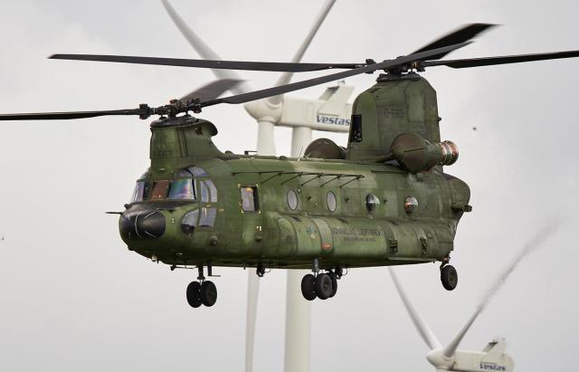 Een Chinook vliegt voor een windturbine