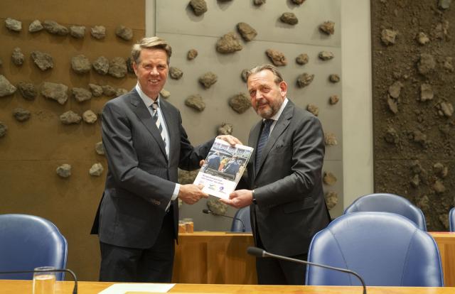 Nationale ombudsman Reinier van Zutphen overhandigt een document aan Kamervoorzitter Martin Bosma. Beiden staan in vak K van de plenaire zaal.