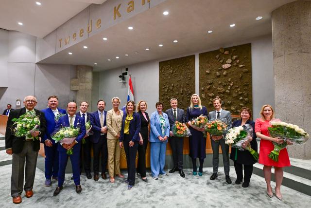 De nieuwe Kamerleden staan op een rij. Sommige houden bloemen vast.