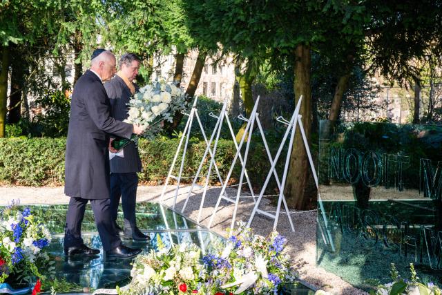 Voorzitter Martin Bosma en Eerste Kamervoorzitter Jan Anthonie Bruijn dragen samen een krans terwijl zij naar de standaard lopen. Op de grond liggen meerdere bloemstukken.