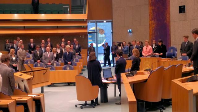 Kamerleden en medewerkers staan in de zaal